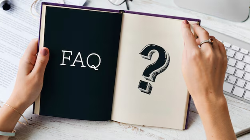 A person holding an open book. The left page is black with the word "FAQ" written in white, while the right page is white with a large, bold question mark. 