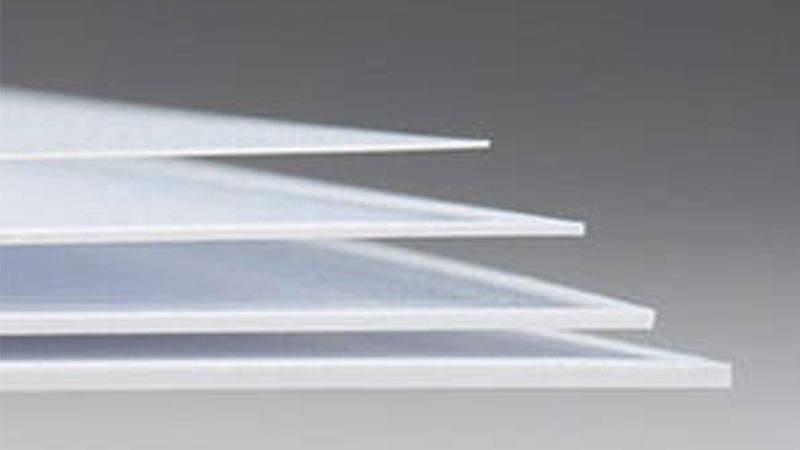 A set of polystyrene sheets in varying thicknesses, commonly used to make clear plastic envelopes, laid out to show the differences in durability and flexibility. The sheets are transparent and glossy.