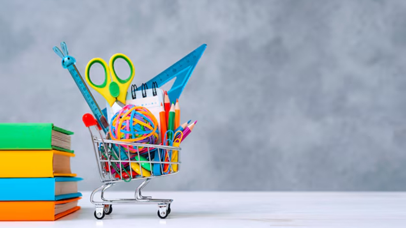 Colorful school supplies in the shopping basket on a gray background 